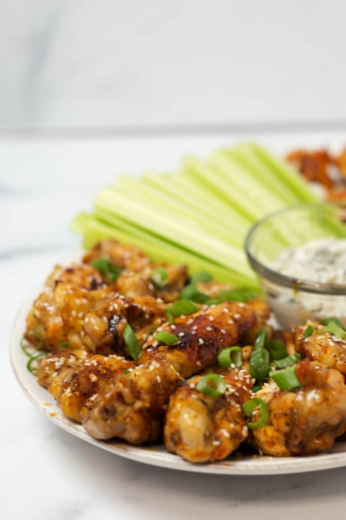 Up close view of teriyaki chicken wings garnished with sesame seeds and green onoins
