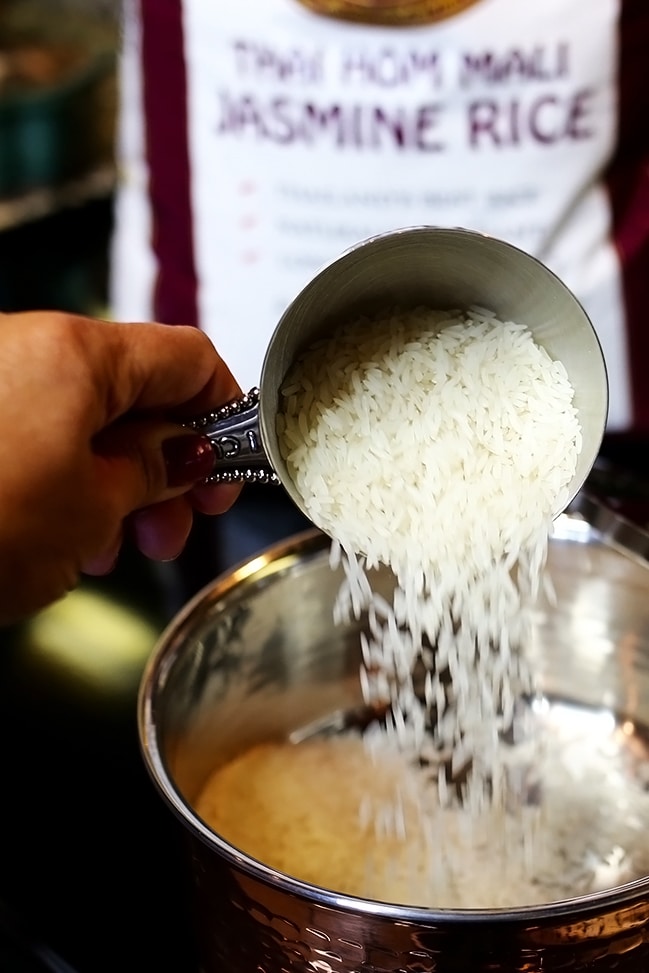 Pouring rice into a pan from a measuring cup