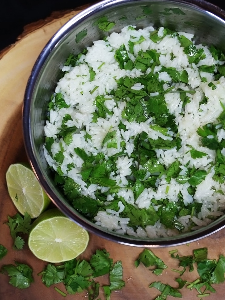 Overhead view of a pan of cilantro lime rice and a lime cut in half