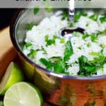 A copper pan of white rice with chopped cilantro and a lime cut in half