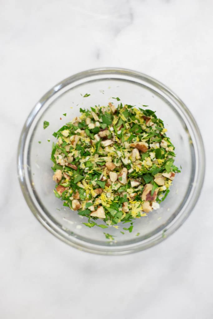 Overhead view of a clear bowl with pecan gremolata
