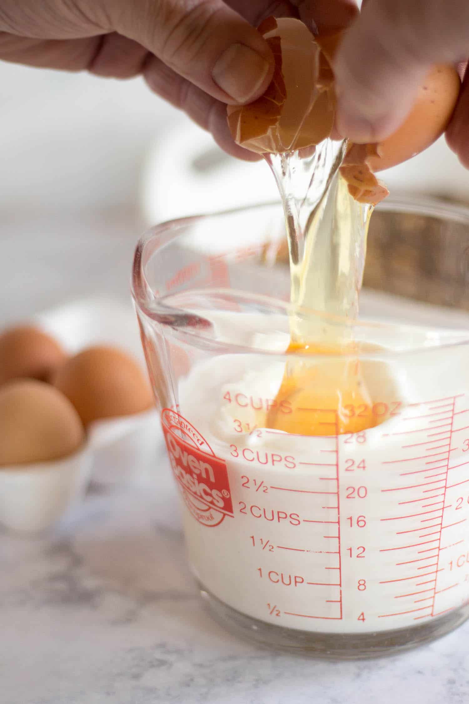 Cracking egg into cup of milk
