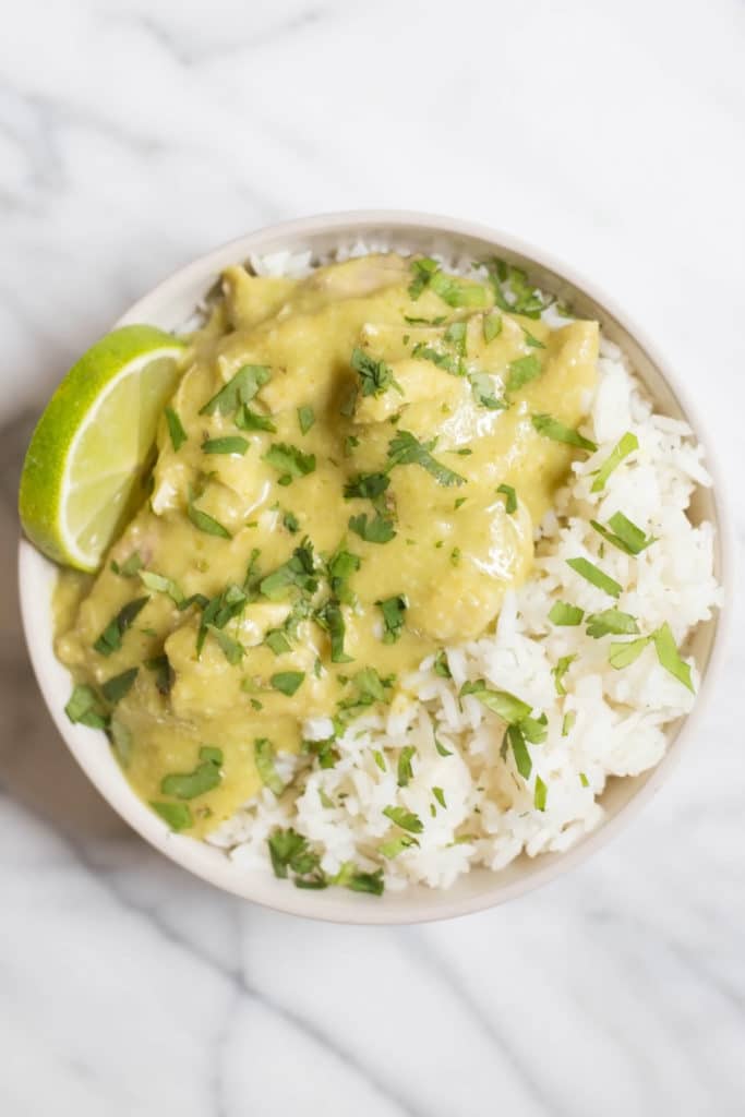 White bowl of Guatemalan stew over rice with a wedge of lime