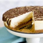 A white cake stand topped with cheesecake with a missing slice