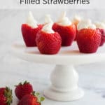A white cake stand topped with cream cheese filled strawberries
