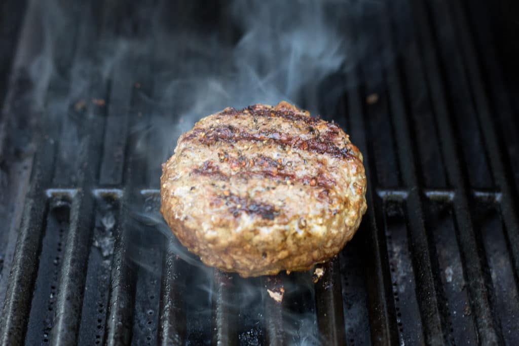 Hamburger on a grill with steam coming off of it