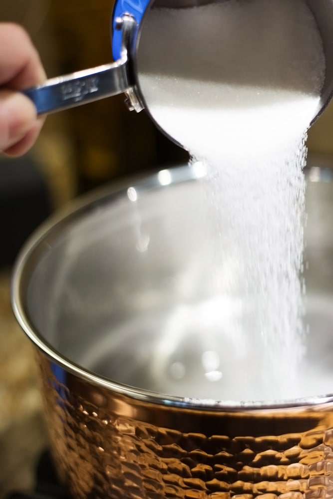 Pouring sugar into a copper saucepan