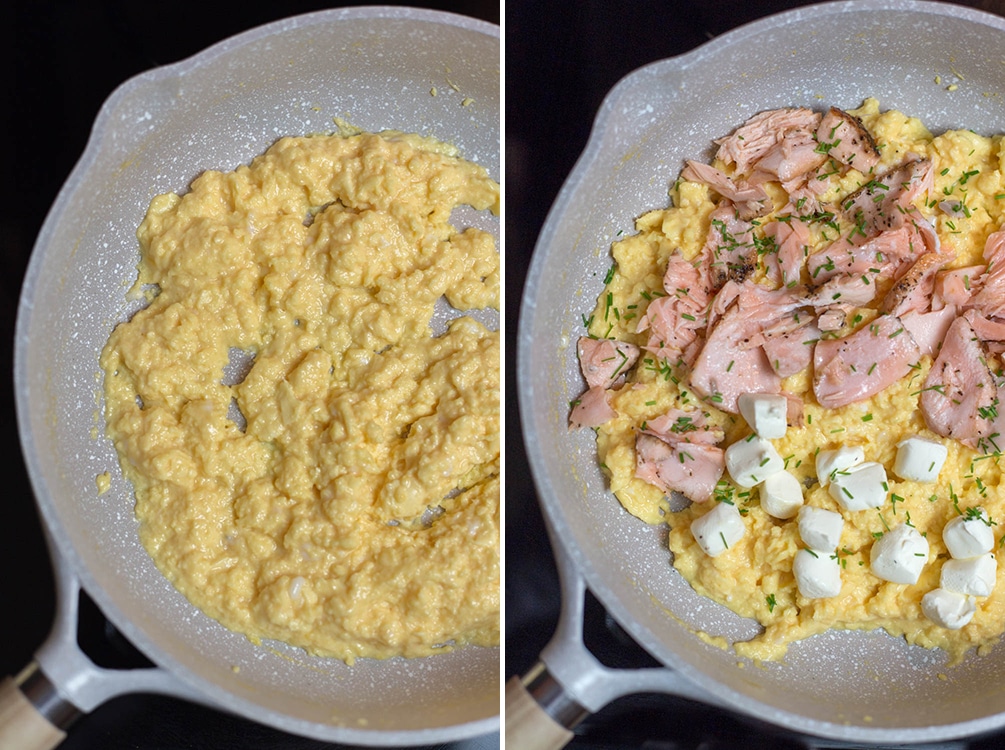 Side by side skillets, one with partially cooked scrambled eggs, one with partially cooked scrambled eggs, salmon, and cubes of cream cheese