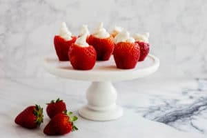 Cream cheese filled strawberries on a white cake stand