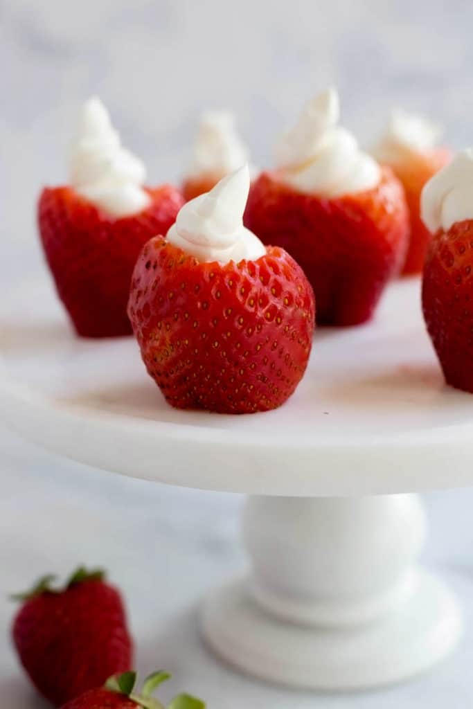 Cream cheese filled strawberries on a white cake plate