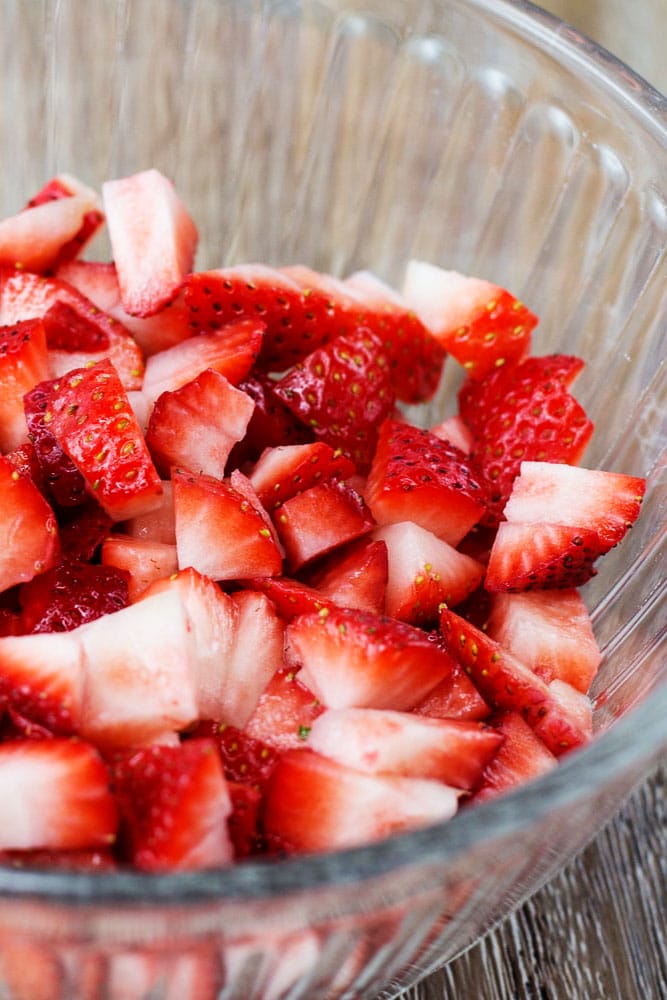 A clear bowl of chopped strawberries