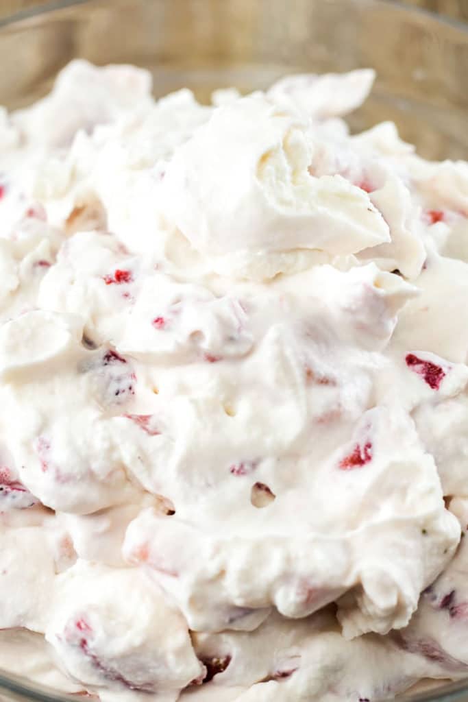 Up close view of whipped cream with chopped strawberries stirred in 
