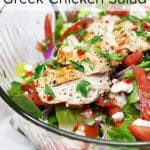 A clear bowl of a salad with tomatoes, feta cheese, and sliced chicken