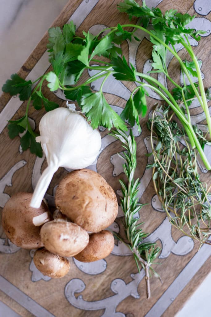 Mushrooms, garlic, and herbs on a cutting board