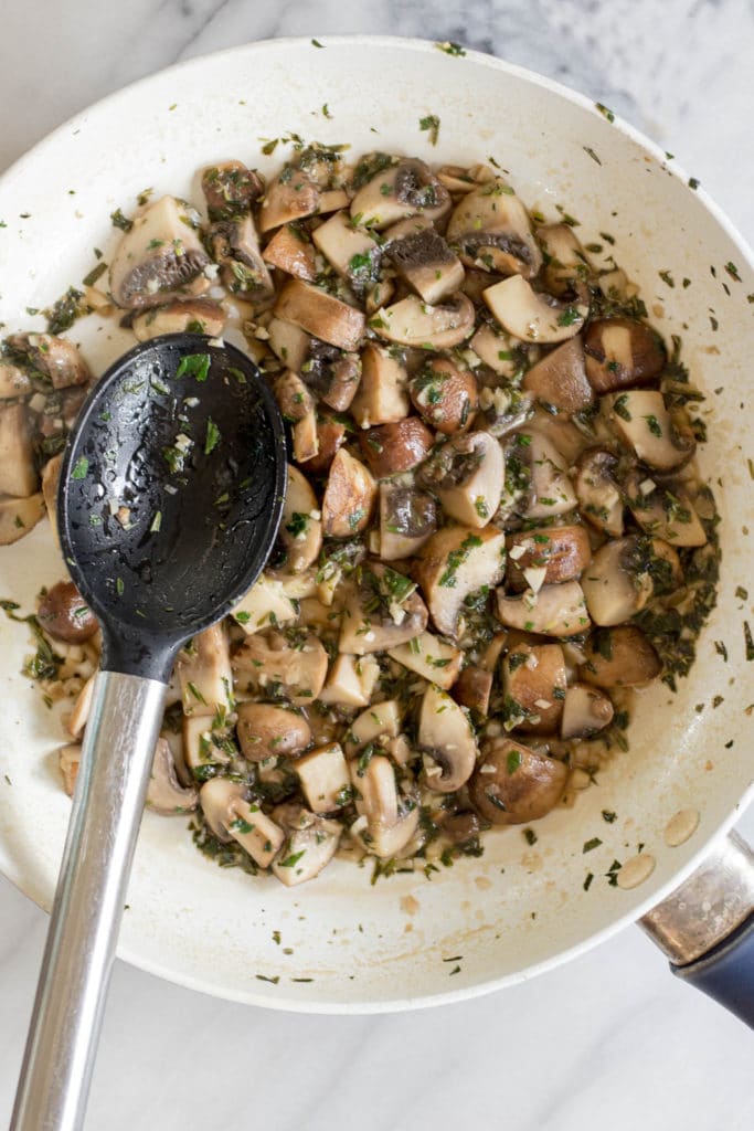 Overhead shot of cooked mushroom mixture in a white skillet