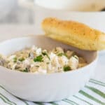 White bowl of mushroom and goat cheese pasta with breadstick