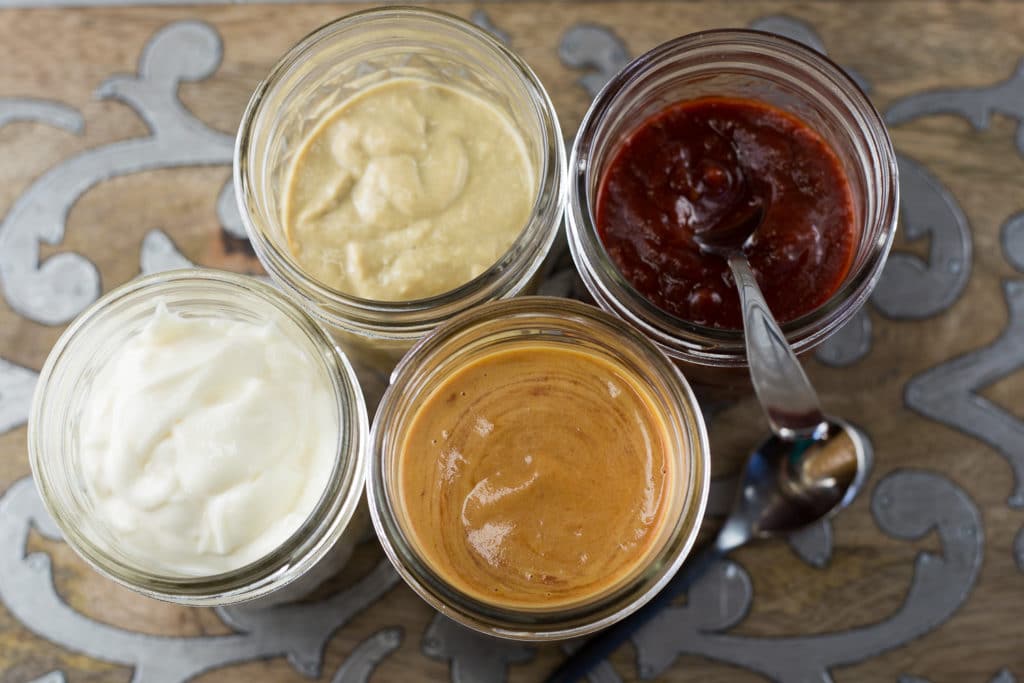 4 open mason jars with different condiments