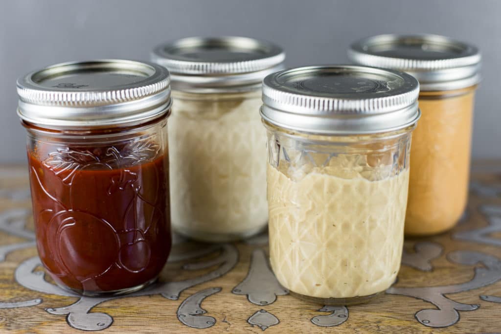 4 mason jars with lids filled with different condiments