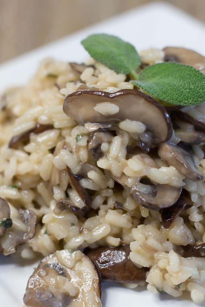 Up close view of mushroom risotto garnished with a sage leaf