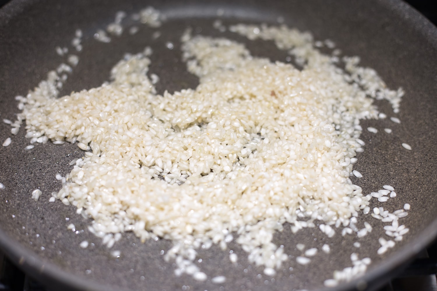 A gray skillet of arborio rice coated in oil