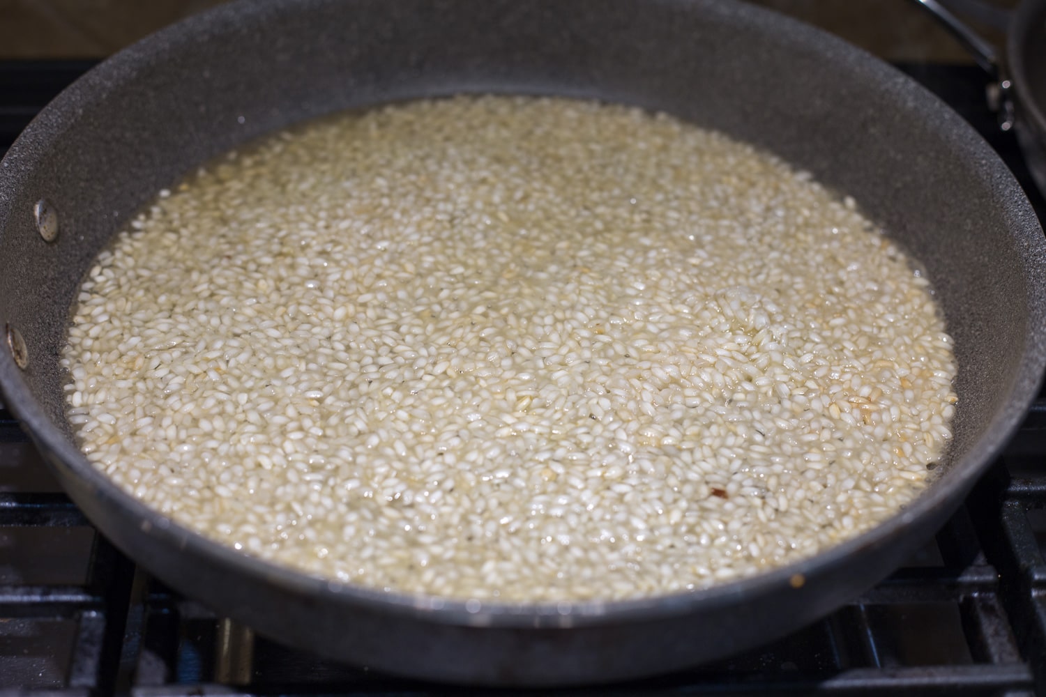 A gray skillet with partially cooked arborio rice