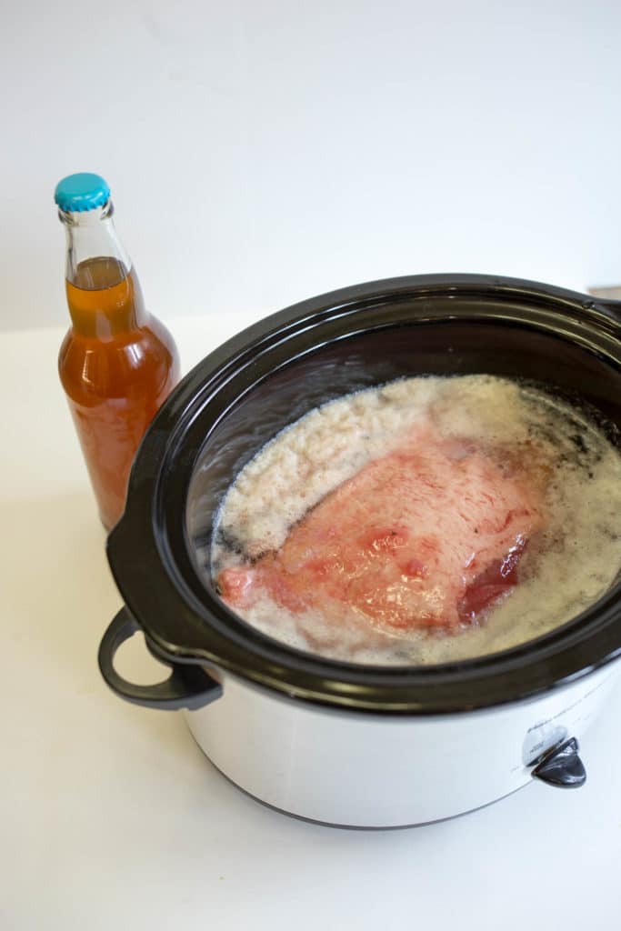 Crockpot with beer covered corned beef and bottle of beer