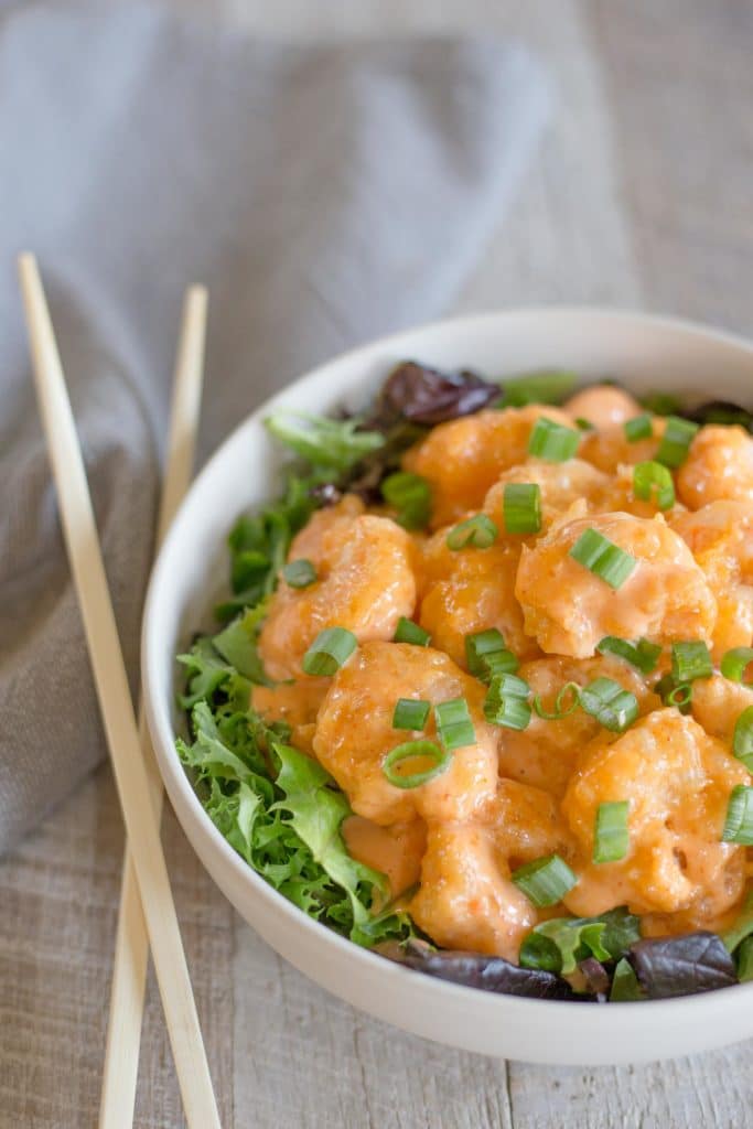 White bowl of firecracker shrimp with chopsticks