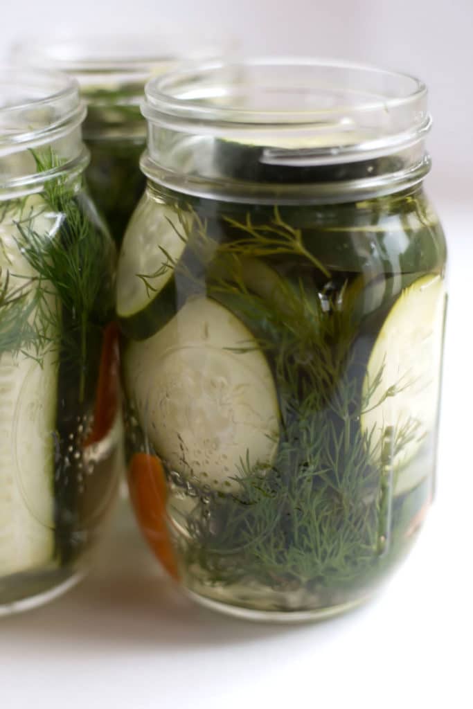 3 open mason jars filled with pickle slices and dill