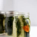 A mason jar filled with pickle spears, dill, and a habanero pepper