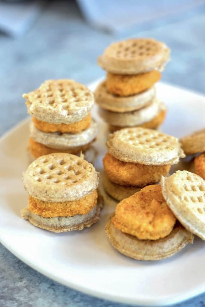 A plate of chicken nuggets sandwiched between miniature waffles