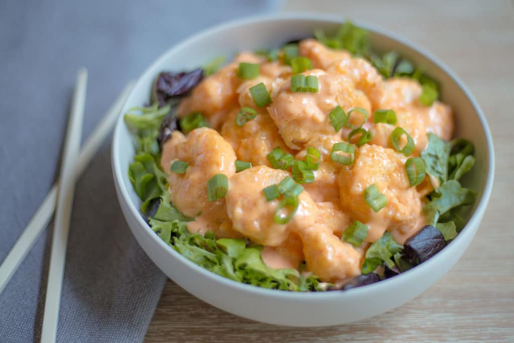 White bowl of firecracker shrimp garnished with green onions