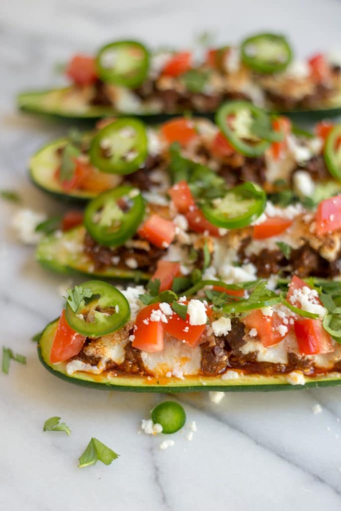 Hollowed zucchini filled with chorizo and topped with cheese, tomatoes, jalapenos, and cilantro