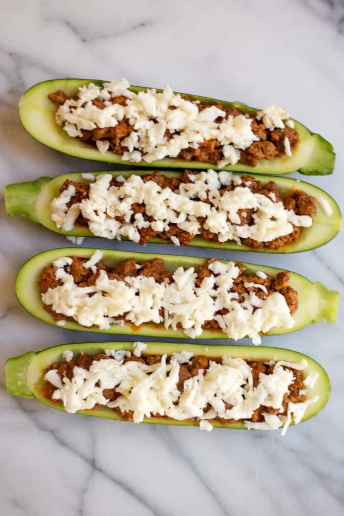Hollowed out zucchini filled with chorizo, topped with grated mozarella cheese