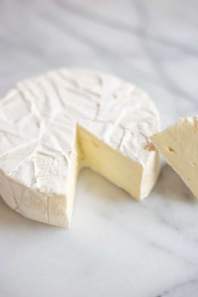 Round of brie cheese with piece cut out
