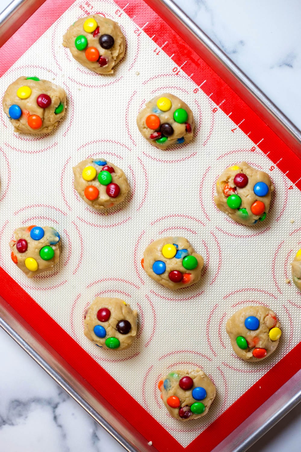 A baking sheet with balls of M&M cookie dough