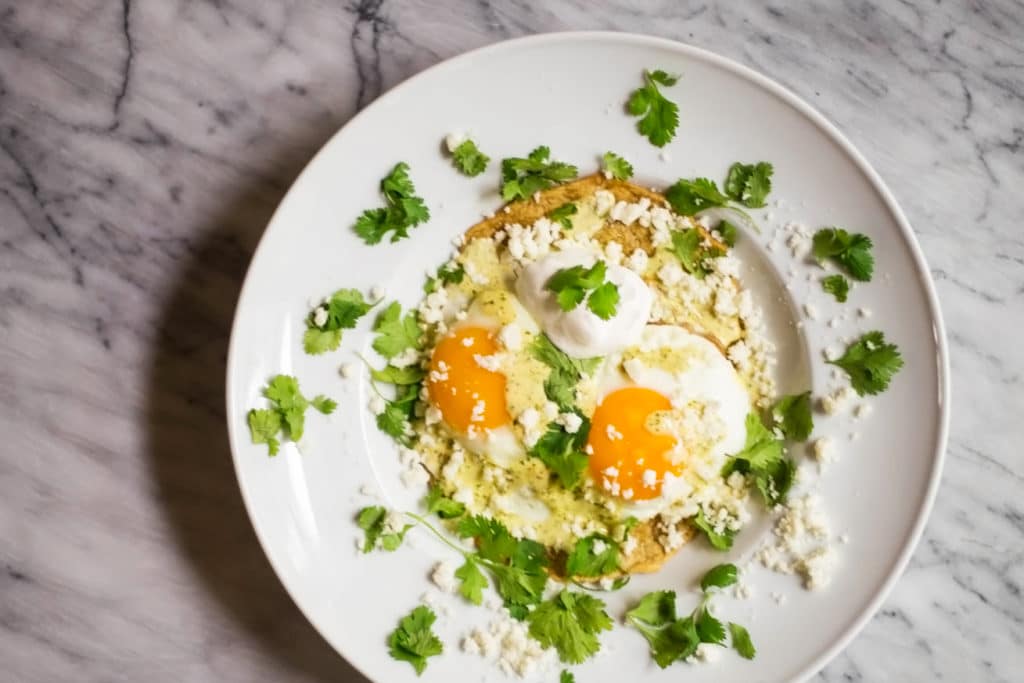 Overhead view of white plate with over easy eggs garnished with chopped cilantro