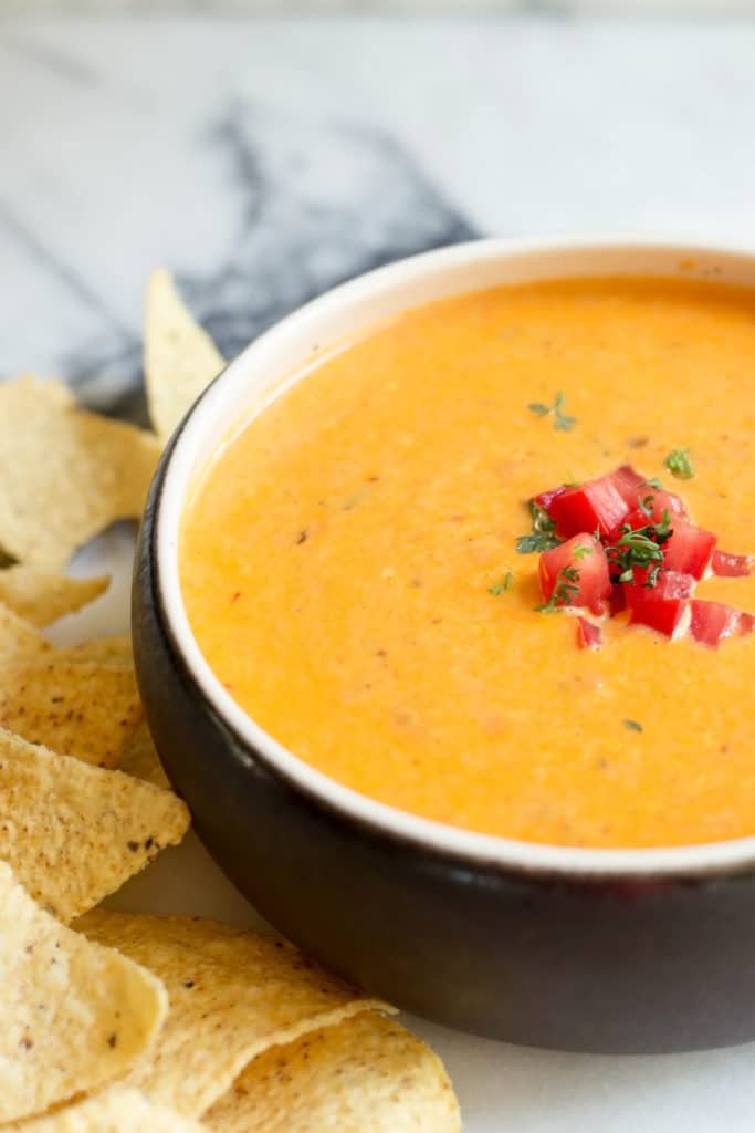 Brown crock of spicy queso dip and tortilla chips