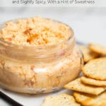 Clear jar of pimento cheese surrounded by crackers