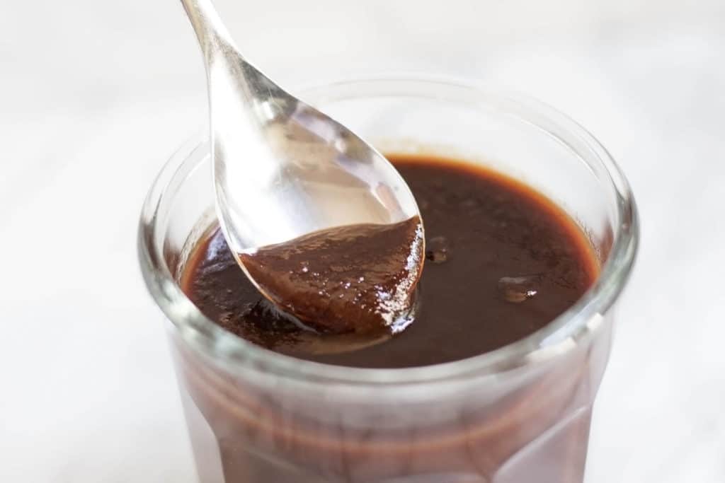 Clear jar of bbq sauce with spoon