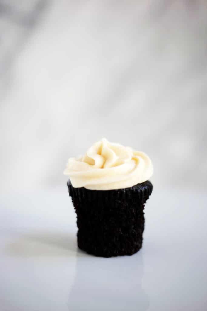 A dark chocolate cupcake with salted caramel frosting on a white board