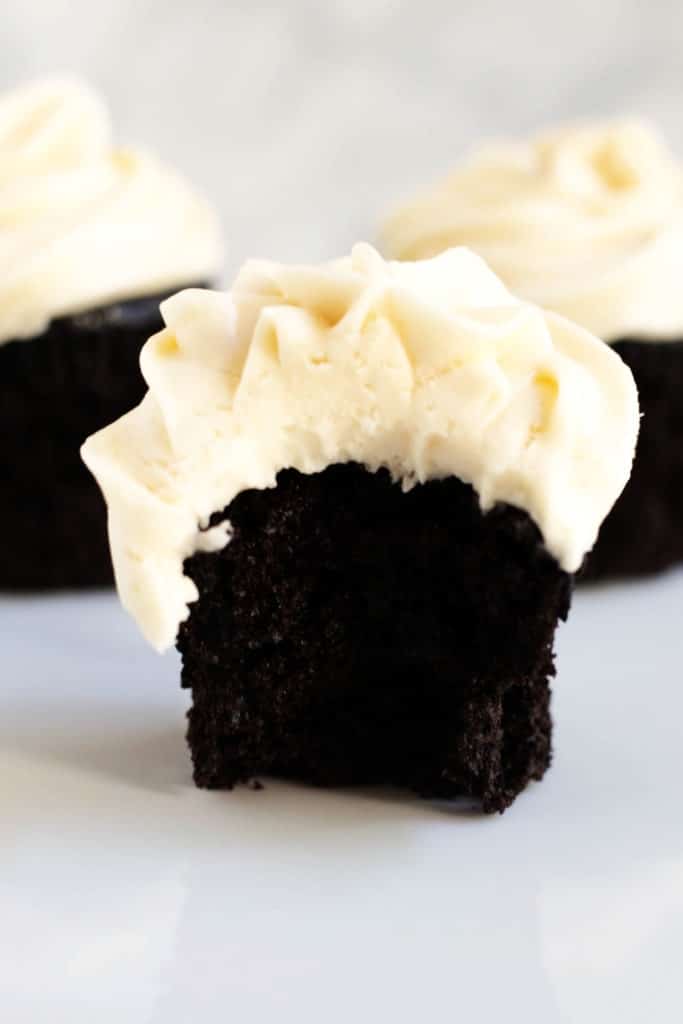 A dark chocolate cupcake with salted caramel frosting with a bite out of it