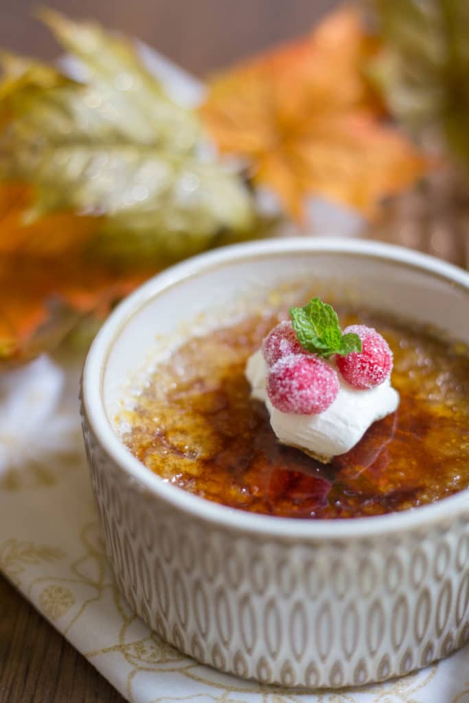 A ramekin of creme brulee garnished with whipped cream and cranberries