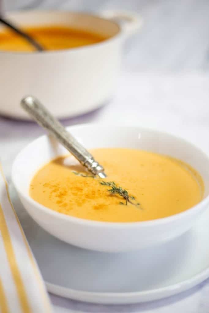 White bowl of lobster bisque with large dutch oven in background