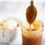 Clear jar of caramel sauce with a spoon