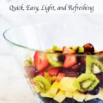 A clear bowl filled with pineapple, kiwi, strawberries, and grapes