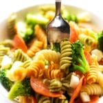 A silver fork scooping pasta salad from a white bowl
