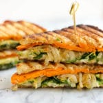 A toasted vegetable sandwich cut in half and stacked with a toothpick in the top