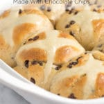 A white baking dish filled with baked hot cross buns made with chocolate chips