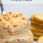 A clear jar filled with pimento cheese and a spoon