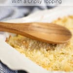 A wooden spoon on top of a white baking dish filled with a casserole that is topped with toasted bread crumbs